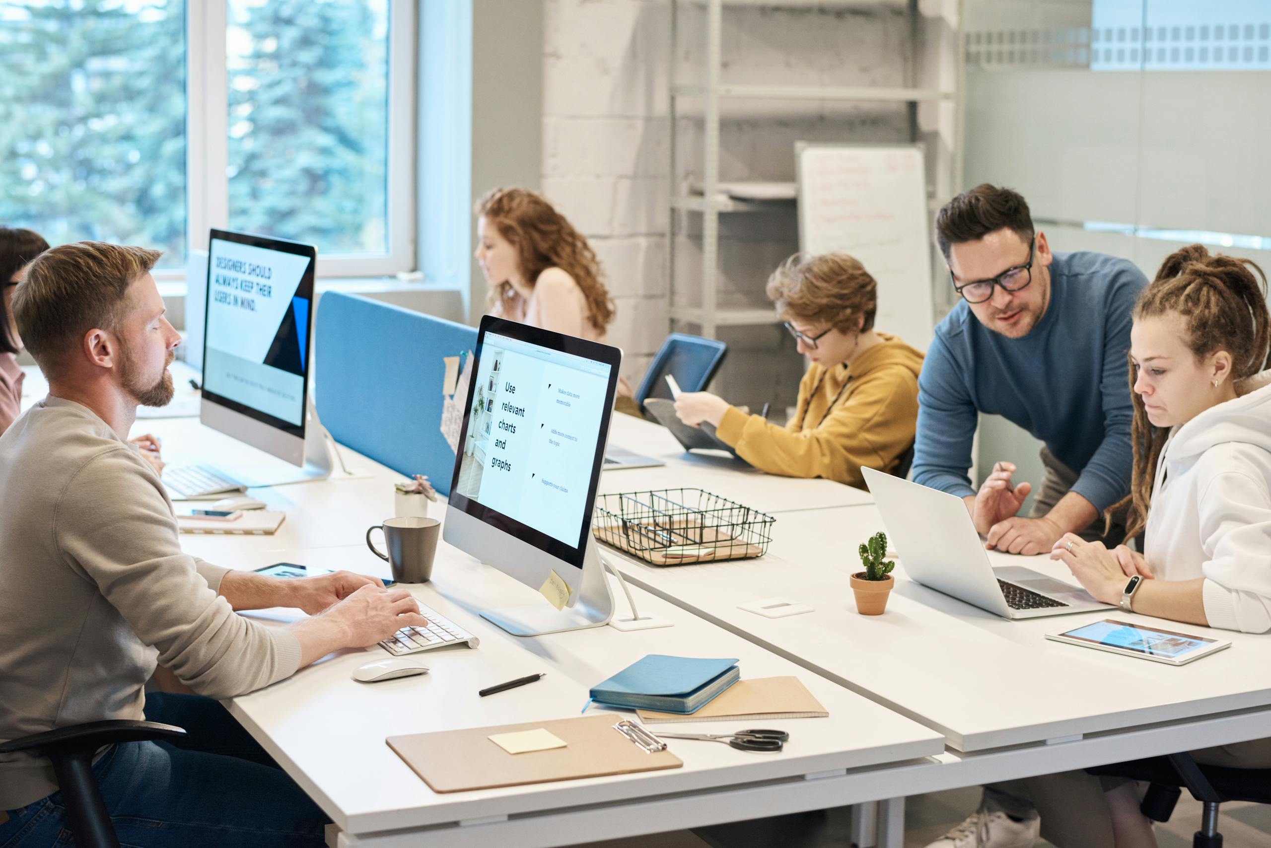 Team collaboration in an office setting with computers and diverse employees working together.